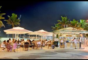 里约热内卢Loft Praia de Copacabana的一群人坐在海滩上遮阳伞下的桌子上