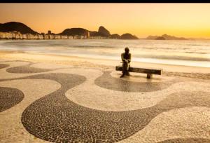 里约热内卢Loft Praia de Copacabana的坐在海滩长凳上的人