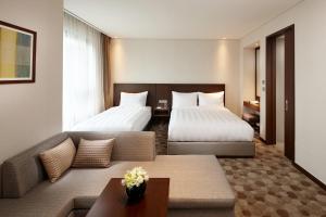 蔚山LOTTE City Hotel Ulsan的酒店客房,设有两张床和一张沙发