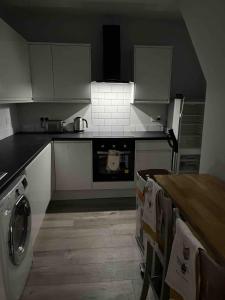 贝里COSY 1 -The Lodge的厨房配有白色橱柜和炉灶烤箱。
