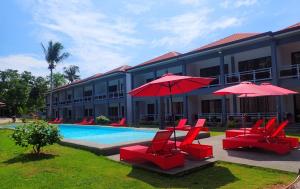 邦劳ANGEL'S DREAM RESIDENCE的游泳池旁的一间酒店,配有红色的椅子和遮阳伞