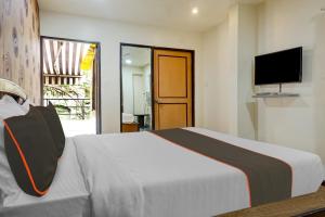 浦那OYO 82148 Hotel Galaxy Residency kalyani nagar的卧室配有一张床,墙上配有电视。