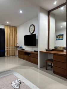 Ban Mae NamApartment的客厅配有电视和墙上的时钟