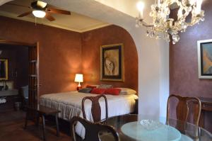 科利马Hotel Art Gallery Casona de los Milagros的一间卧室配有一张床、一张桌子和一个吊灯。