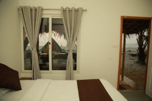 阿勒皮Havana Beach House的一间卧室设有一张床和一个享有海滩美景的窗户。