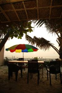 阿勒皮Havana Beach House的海滩上一张带五颜六色遮阳伞的桌子