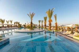 贝莱克Kirman Belazur Resort & Spa的棕榈树和椅子的度假村的游泳池
