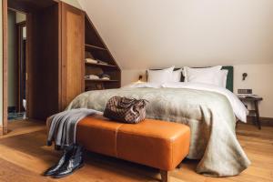 施伦斯Posthotel Taube的一间卧室配有一张床,另一间卧室配有带袋子的搁脚凳