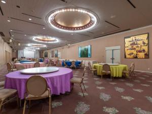 堺市Tabist Hotel Liberty Plaza的宴会厅配有桌椅、紫色和黄色桌子