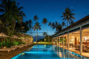 本托塔Taru Villas The Long House - Bentota的棕榈树度假村前的游泳池