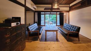 长野Kominkahu kashikiri cottage Tokei - Vacation STAY 57497v的一间设有两张长椅和一张桌子及椅子的房间