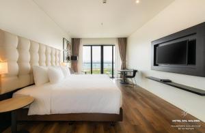 下龙湾Hotel Soleil Ha Long, Trademark Collection by Wyndham的卧室配有一张白色大床和一台平面电视。