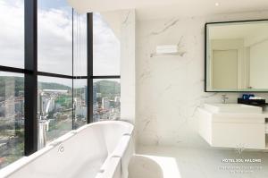 下龙湾Hotel Soleil Ha Long, Trademark Collection by Wyndham的带浴缸、水槽和镜子的浴室