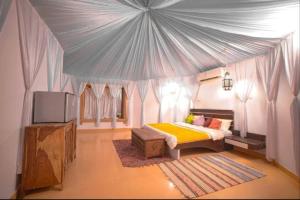 斋沙默尔Luxury The Sunrise Resort with swimming pool Jaisalmer的一间卧室设有一张帐篷、一张床和一台电视机