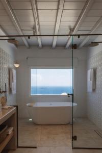 圣爱奥尼斯米科诺斯Birdhouse Private Luxury Suite的带浴缸的浴室和大窗户