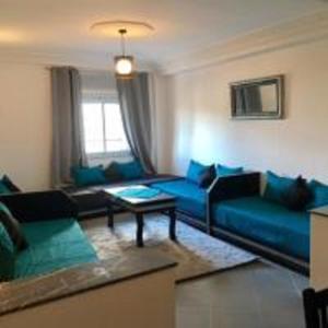 丹吉尔Appart Hôtel Tanger Paname的客厅配有蓝色的沙发和桌子