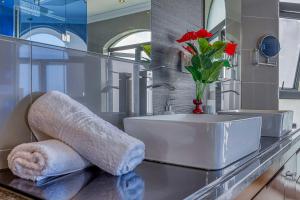 约翰内斯堡Villa Tasha Luxury Suites, Lanseria的浴室设有水槽和鲜花花瓶
