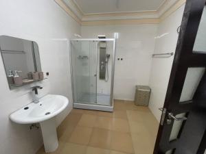 OgbojoEden Court Luxe的一间带水槽和玻璃淋浴的浴室