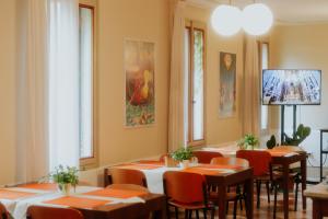 威尼斯卡萨艾卡达米亚旅舍的餐厅设有橙色桌椅和窗户。