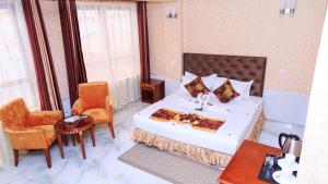 内罗毕肯尼亚轻松酒店的一间卧室配有一张大床和两把椅子