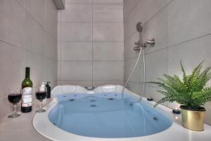 萨法德סוויטת גן עדן - Gan Eden Suite的浴缸,配有两杯葡萄酒和一株植物