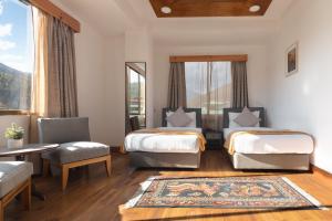 廷布Hotel Dralha的一间设有两张床和一张桌子及椅子的房间
