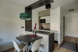 斯玛杰克托莱塞Apartma Vitalis的厨房配有黑桌和白色椅子