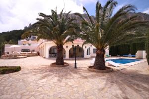 卡尔佩Villa Alicia - PlusHolidays的两棵棕榈树和一座游泳池的房子