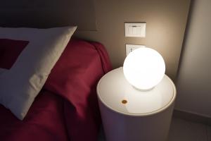 朱利亚诺瓦泽尼特酒店 的床头桌旁的灯和枕头
