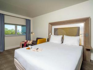 南特诺富特南特中心火车站酒店的酒店客房设有一张白色大床和椅子