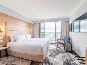 悉尼Novotel Sydney Brighton Beach的一间酒店客房,配有一张床和一台电视