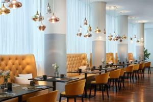 美因河畔法兰克福Avani Frankfurt City Hotel - previously NH Collection Frankfurt City的用餐室配有桌椅和吊灯。