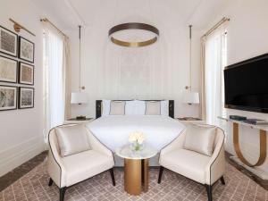 麦纳麦Raffles Al Areen Palace Bahrain的一间卧室配有一张床、两把椅子和一张桌子