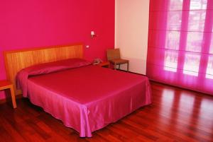 圣安蒂奥科伊科罗利酒店的红色卧室配有一张带粉红色床罩的床