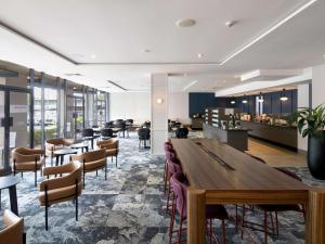 布里斯班Mercure Brisbane Garden City的餐厅设有一张大型木桌和椅子