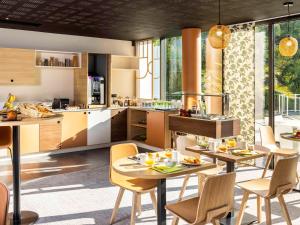 阿让Mercure Agen Centre的厨房以及带桌椅的用餐室。