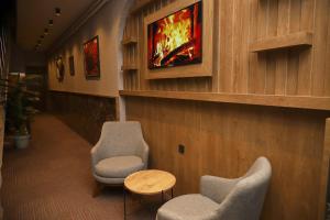 TokatRush Hotel Tokat的一间设有两把椅子和一台墙上电视的等候室