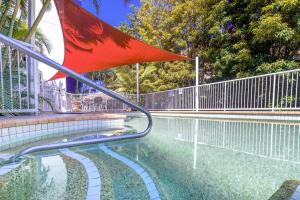 黄金海岸Freshly Renovated Modern Waterfront 1 Bedroom unit的围栏旁的游泳池,带红旗