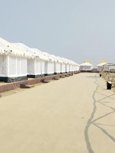 DhordoRann Heritage Resort的长排带桌子和遮阳伞的白色帐篷