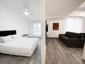 欧奈索斯博伊斯Résidence 4T IMMO - 31 Avenue Gaston Chauvin的卧室配有白色的床和黑色沙发