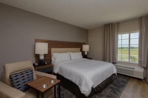 波特兰Candlewood Suites - Corpus Christi - Portland, an IHG Hotel的配有一张床和一把椅子的酒店客房