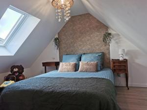 PlouigneauLes gîtes de L'hermine的一间卧室配有一张带蓝色床单和吊灯的床。