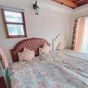 恩纳猫とピアノと星空のリゾートブティックコテージ - Starry Forest Cottage Okinawa -的一间卧室配有一张带花卉床罩的大床
