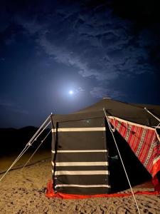 迪拜Sahara INN Smart Resort & Camping的夜间在海滩上坐的帐篷