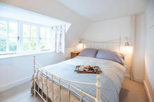 伍德布里奇The Pink Cottage, Blaxhall的卧室配有白色的床,并备有托盘