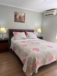 圣地亚哥Isabel Suites Vitacura的一间卧室配有一张带粉色和白色被子的床
