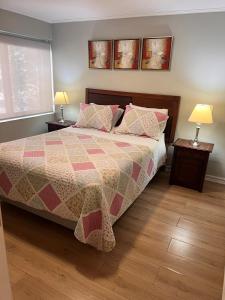 圣地亚哥Isabel Suites Vitacura的一间卧室配有一张带被子和两盏灯的床。