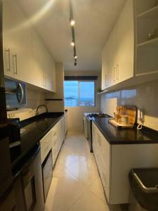 巴拉那州蓬塔尔Lindo Apto com vista para o Mar!的厨房配有白色橱柜和黑色台面