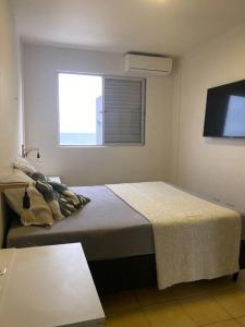 巴拉那州蓬塔尔Lindo Apto com vista para o Mar!的一间卧室设有一张床、一个窗口和一台电视