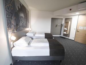 维也纳新村B&B HOTEL Wiener Neudorf的酒店客房设有两张床,墙上挂有绘画作品